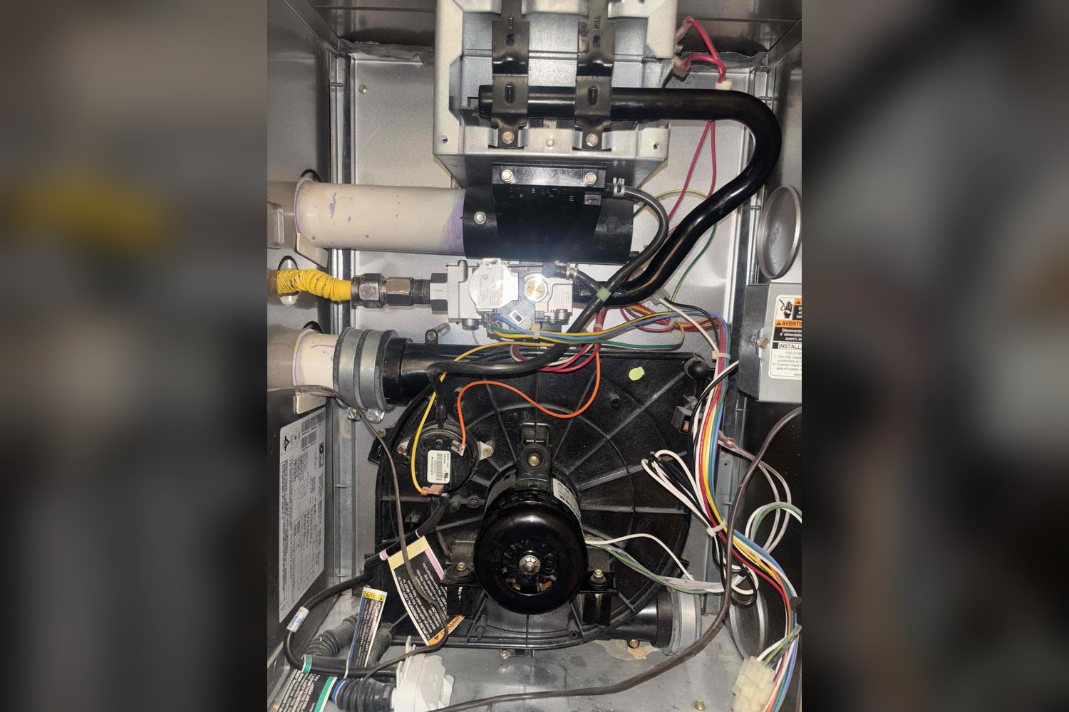 Open furnace cabinet showing inducer motor and gas valve during service