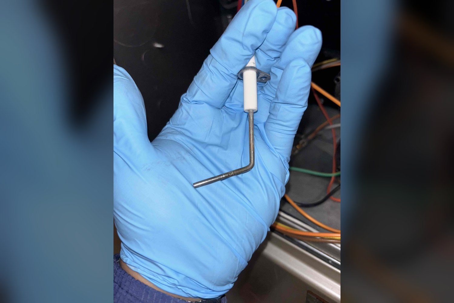 EscoCool technician holding a furnace flame sensor during inspection