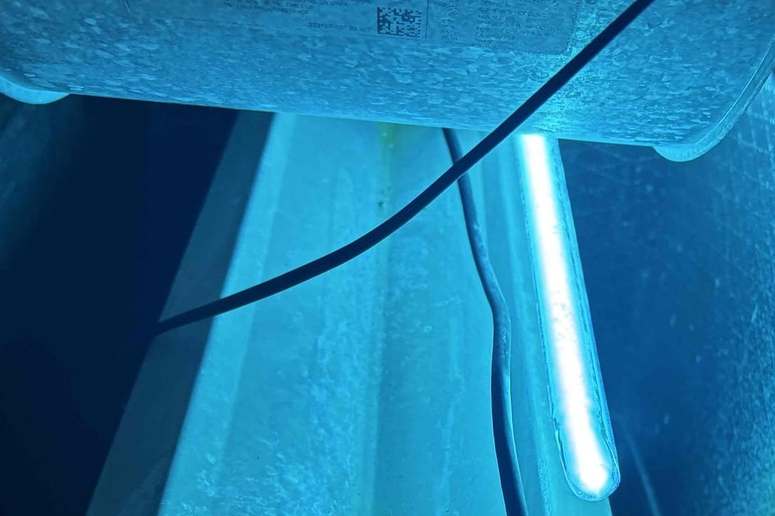 UV-C sterilization lamp installed and glowing inside an air handler cabinet